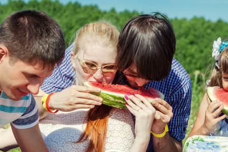 快乐的情侣一起野餐吃西瓜, 一起玩得开心。户外肖像