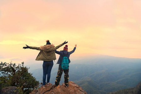 徒步旅行者夫妇与背包站立在山顶和享受自然看法