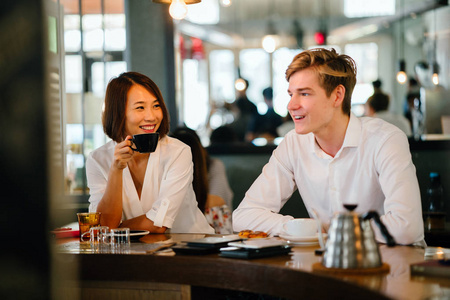 中国人微笑中国亚裔妇女正在和一个年轻的白种男人喝咖啡.