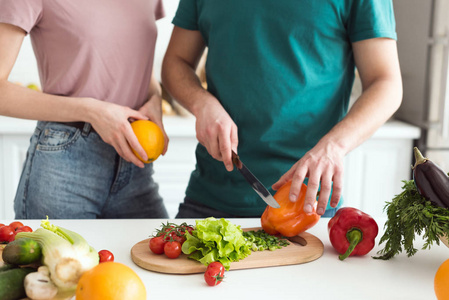 裁剪图像的男朋友切蔬菜素食沙拉在厨房
