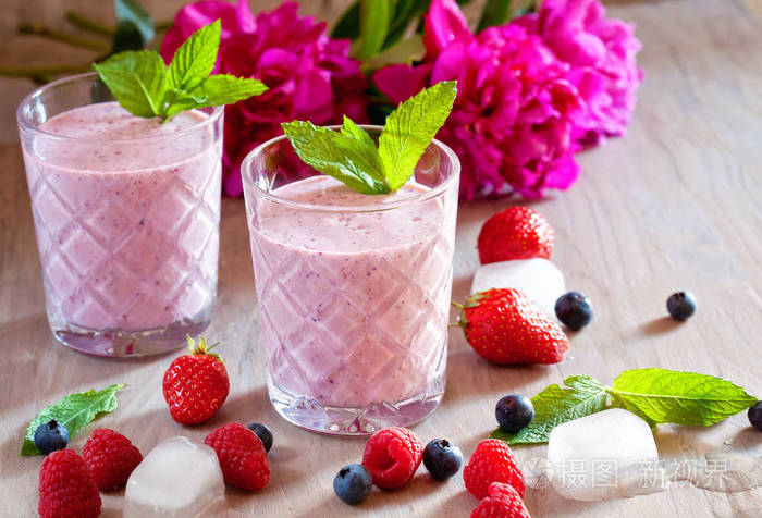 美味的蓝莓, 草莓, 覆盆子和酸奶果汁与浆果和薄荷周围的木质背景