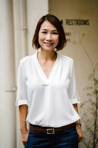 一位亚洲华人女经理的肖像在白天站着。她在白天站在走廊里, 自信地微笑着。