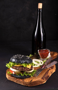 新鲜的自制汉堡木制服务板上用刀和叉番茄汁和 vitage 瓶在深色背景上