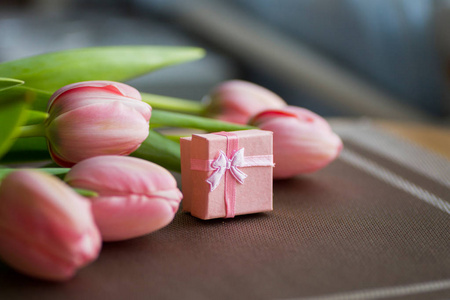 束粉红色郁金香与桌上的礼品盒