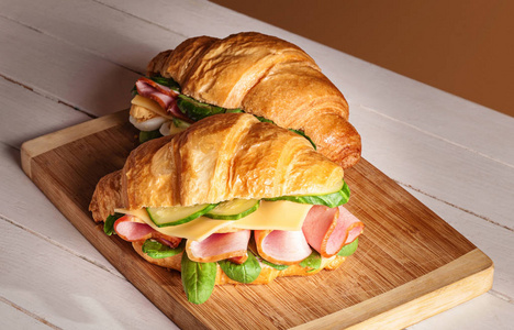 羊角面包三明治在木砧板上。在前面的羊角面包三明治上选择性焦点