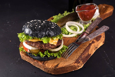 木制服务板上茄汁刀和叉在深色背景上的新鲜自制汉堡