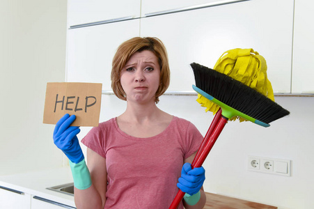 女人在自家厨房手套与清洁扫帚和拖把寻求帮助