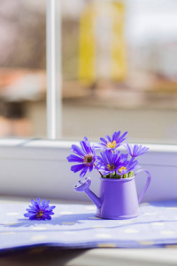 与春天鲜花花束靠近窗户的小喷壶