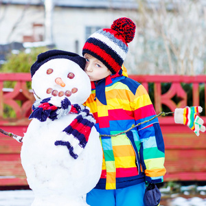 有趣的孩子男孩在冬天堆雪人