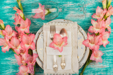 餐具和银器与天蓝色背景光粉红色唐菖蒲