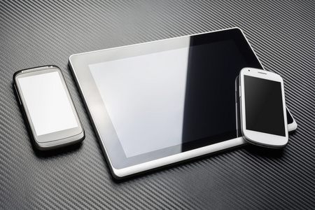 空白黑手机躺在商务平板电脑旁与反射和上它的角落里，都在以上碳层的白色智能手机