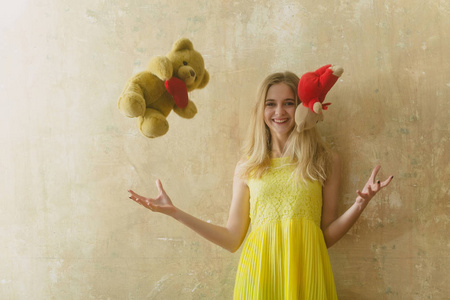很快乐的女孩穿着黄色连衣裙的泰迪熊玩具