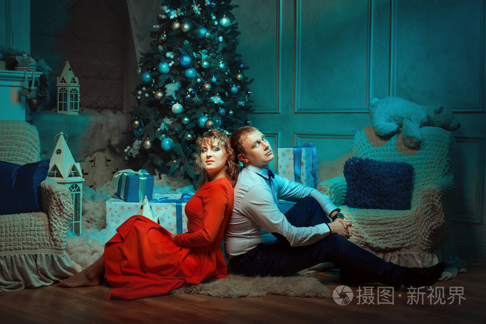 对年轻情侣坐在圣诞树下