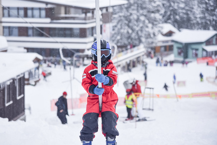 六年岁小滑雪男孩紧紧的抱着到滑雪的句柄