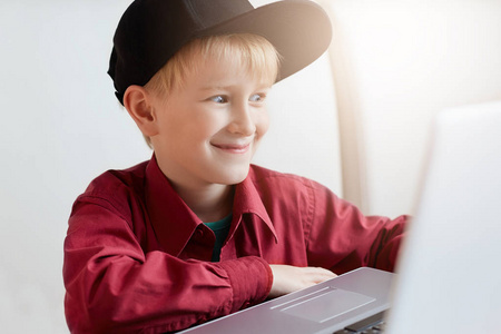 快乐的小男孩在室内看电脑年轻的人类表达可爱的表情