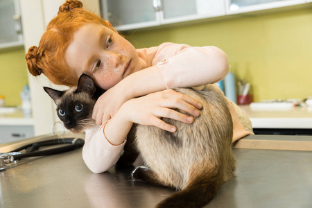 女孩抱着她的猫在兽医诊所