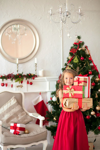 圣诞快乐小女孩微笑着站在圣诞树下的礼物