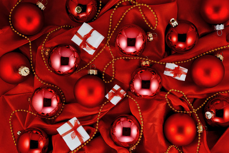 高对比度黑暗豪华的背景红色圣诞树球 小礼品盒和红色闪亮真丝织物上的饰以金