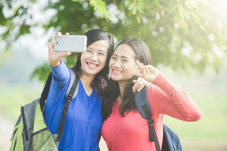 两个年轻的亚裔学生愉快地采取自拍照，