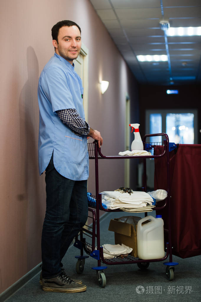 一名男子在宾馆酒店清洁人员正在微笑毛巾真空清洗酒店客房为客人提供