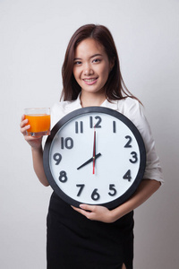 亚裔女子和时钟喝桔子汁