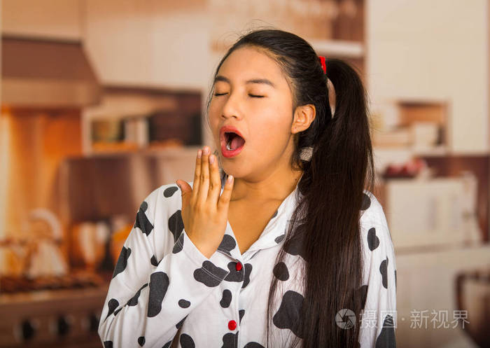 年轻的黑发女人摆睡衣摄像头和打哈欠