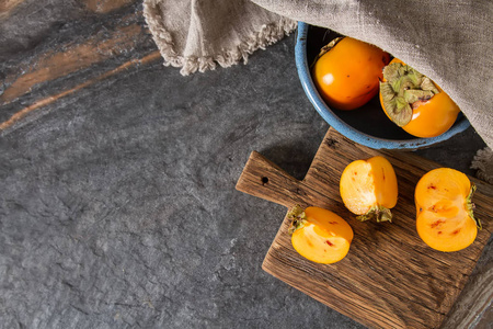 橙色柿子成熟的木托盘上的蓝色碗里。饮食，或