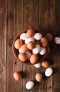 白色和棕色木制背景上的陶瓷碗里的鸡蛋。乡村风格。鸡蛋。复活节的照片概念。Copyspace