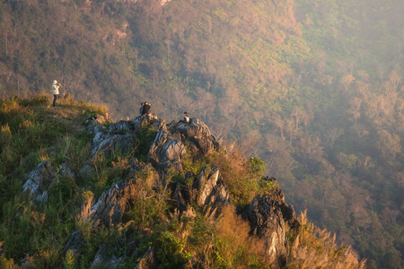 年轻的游客们在欣赏山谷景观从山顶日落期间