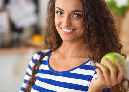 快乐的年轻女人吃苹果在厨房