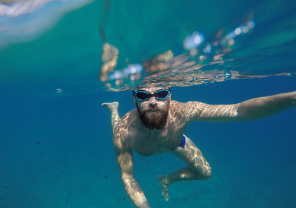 年轻的胡须男人，面罩潜水在干净的水