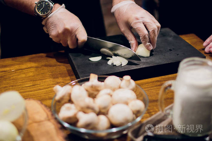 厨师的手用刀子把洋葱放在木板上.准备做饭.健康饮食与生活方式