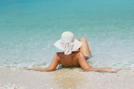 后视图的年轻漂亮的女人，用椰子放松在阳光明媚的热带海滩
