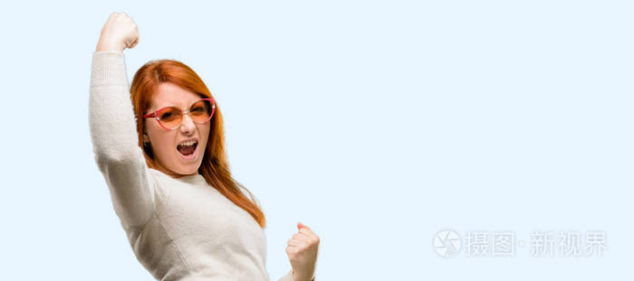 美丽的年轻红发妇女高兴和兴奋庆祝胜利表达了巨大的成功权力能量和