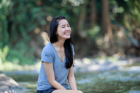 女孩坐在一个瀑布，微笑快乐 软焦点