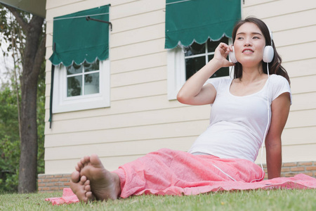年轻的亚裔女子，坐在新鲜的春草听亩