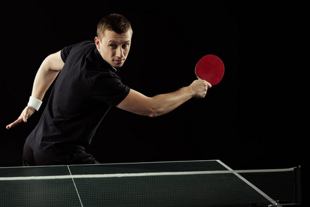 网球运动员的肖像在制服打乒乓球在黑被隔绝了