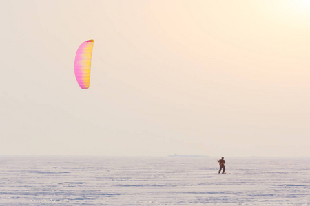 Kitesurfer 在日落前的冬季雪中骑着降落伞