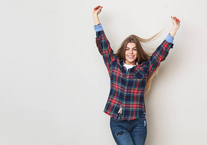 幸福的年轻女人，在靠墙摆姿势的格子衬衫