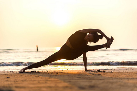 ung frisk kvinna utvar yoga p stranden vid solnedgngen