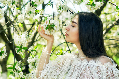 在开花公园的一个年轻女孩的肖像。樱桃花时尚女孩