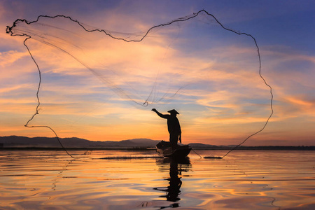 剪影渔夫在钓鱼船设置网与日出