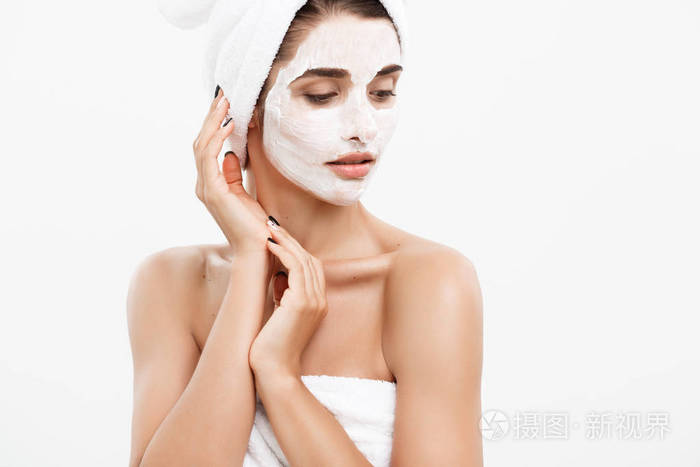 美容护肤理念美丽的白种女人脸上的肖像应用奶油面膜在她的面部皮肤白色背景