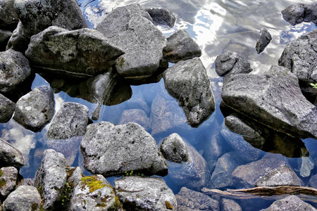 在湖的透明表面上的石头和岩石反射山塔特拉山, 波兰