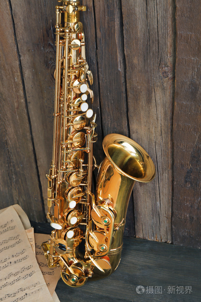 美丽的金色萨克斯与音符在木制的背景下,关闭
