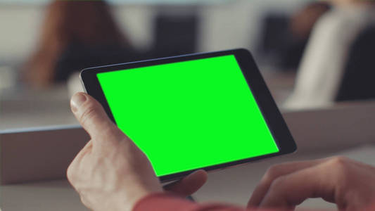 男人用绿色的屏幕看着平板电脑的屏幕。股票。屏幕上的色度键手