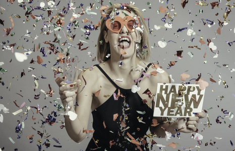 快乐滑稽的金发女郎庆祝新年与香槟和新年标志