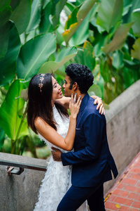 在亚洲, 一个有吸引力的情侣在公园里站在一起。他们正在拍婚礼照片。一个是印度男人, 另一个是中国女人。