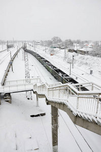 一辆长途货车正沿着铁轨行驶。降雪后冬季的铁路景观
