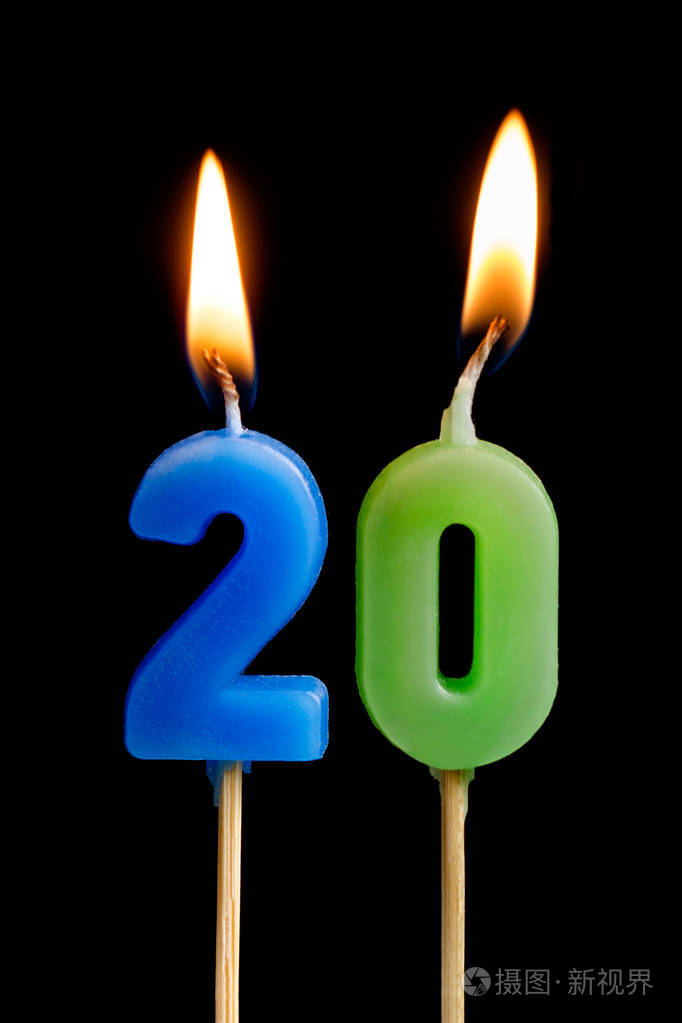 燃烧蜡烛的形式二十数字 (数字, 日期) 的蛋糕被隔离在黑色背景.